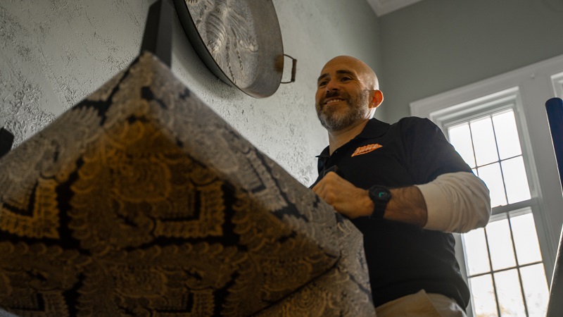 Worker carrying a mattress down stairs inside a home, representing professional mattress disposal service in Philadelphia.