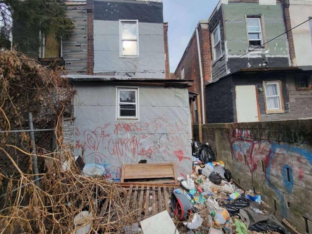 Illegal dumpsite with trash bags and debris behind residential buildings