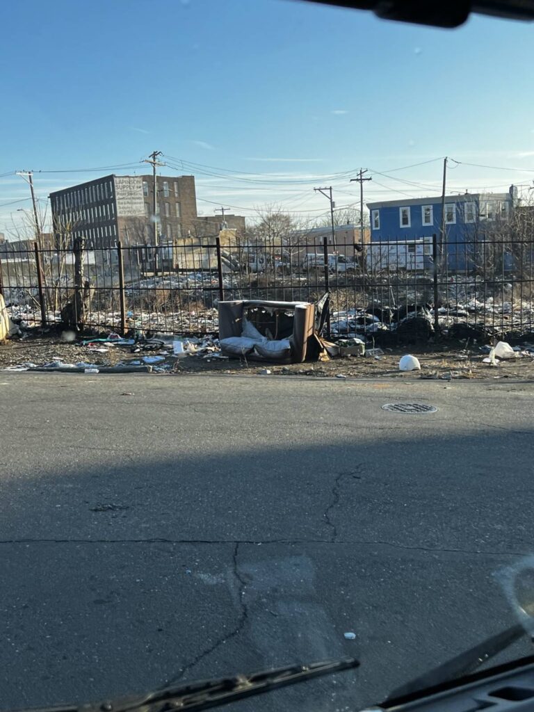 Trash and abandoned furniture in vacant urban lot