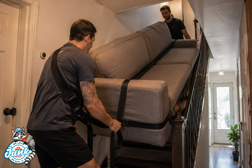 Movers carrying a sofa up a narrow staircase in a rowhome